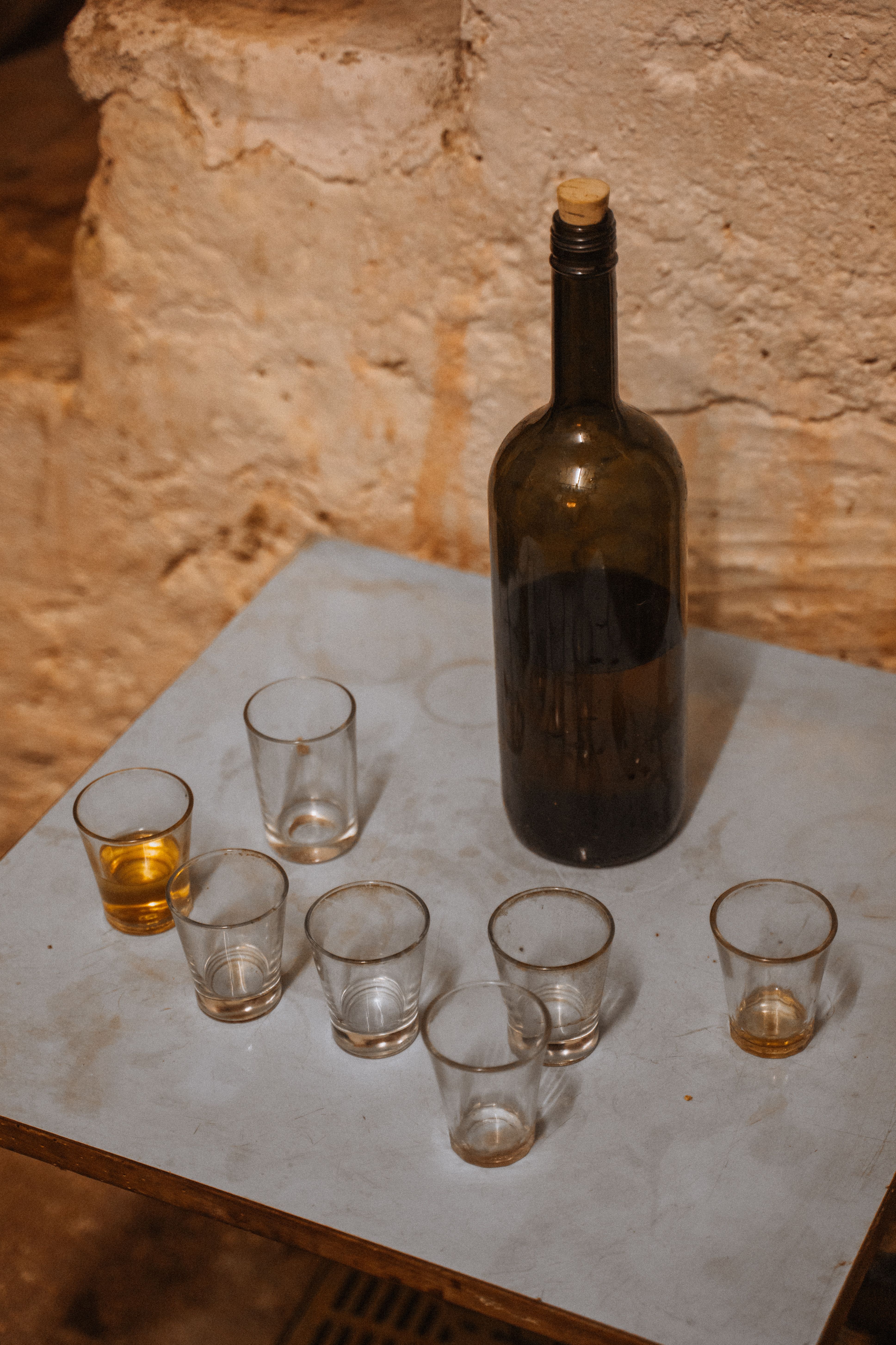 A rustic scene with a vintage wine bottle and empty glasses on a weathered table, evoking Sardinian charm.