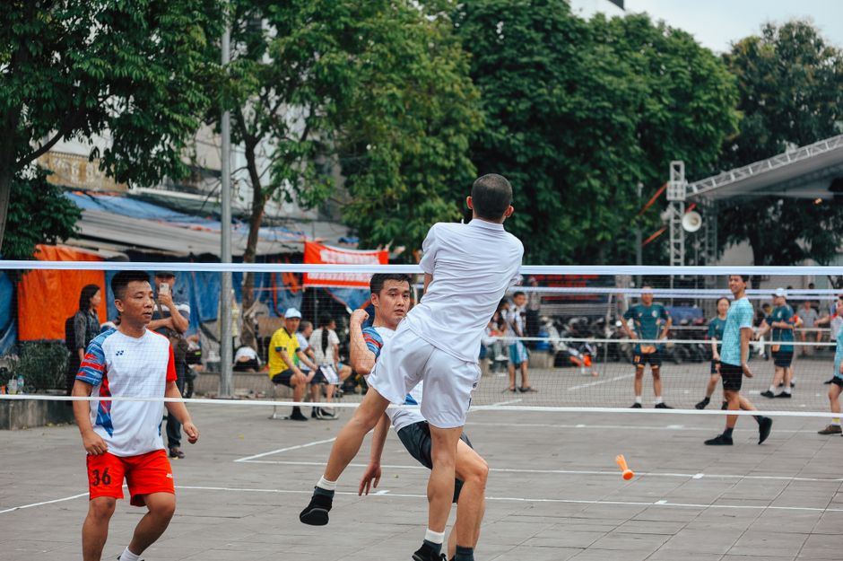 Exciting badminton match outdoors with multiple players engaged in action.