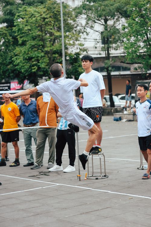 Free A group of men engaging in a dynamic street performance with a man balancing on a stool. Stock Photo