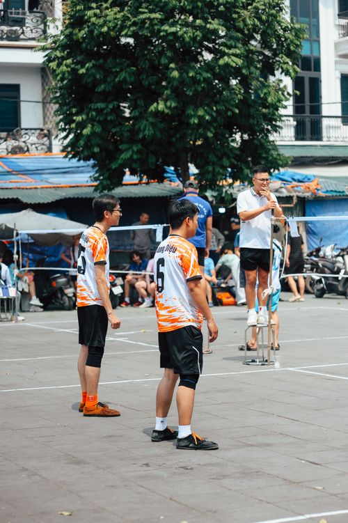 Free Men playing volleyball in an urban outdoor court during the day. Stock Photo