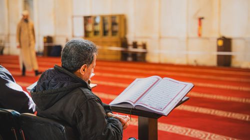 Free A man sitting in a mosque, attentively reading the Quran. Captures a peaceful moment of reflection. Stock Photo