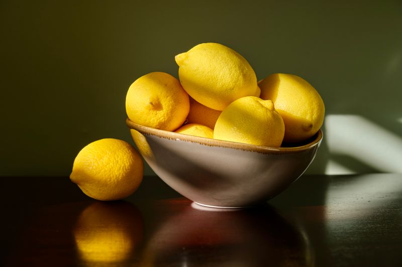 Lemons in a ceramic bowl lit by raking daylight. Photo by WJ Y on Pexels