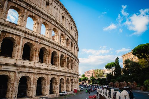 Free View of the Colosseum in Rome, Italy with a vibrant blue sky. A popular tourist attraction and historical landmark. Stock Photo