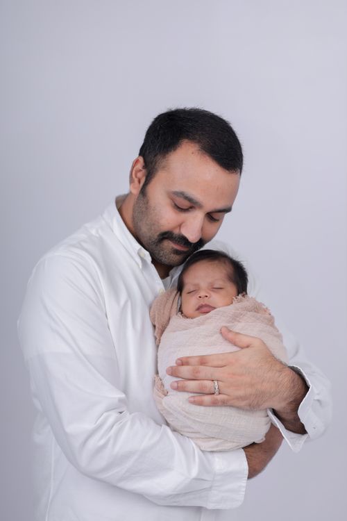 Free Heartwarming portrait of a father tenderly holding his sleeping newborn wrapped in blanket. Stock Photo