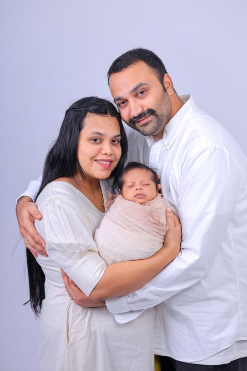Free A loving family portrait featuring a mother, father, and their newborn baby in a warm embrace. Stock Photo