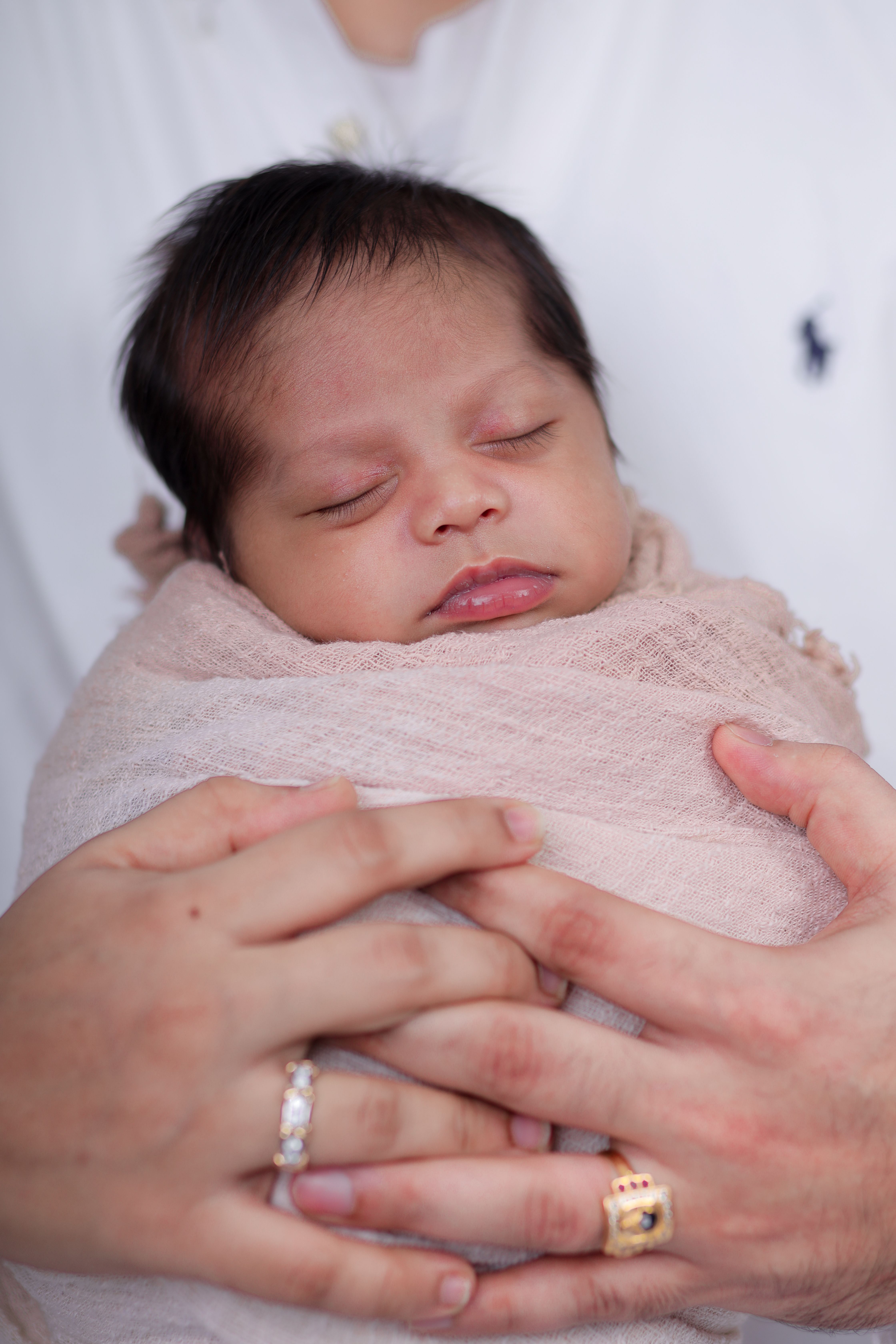 Heartwarming portrait of a sleeping newborn wrapped and cradled in father's hands.