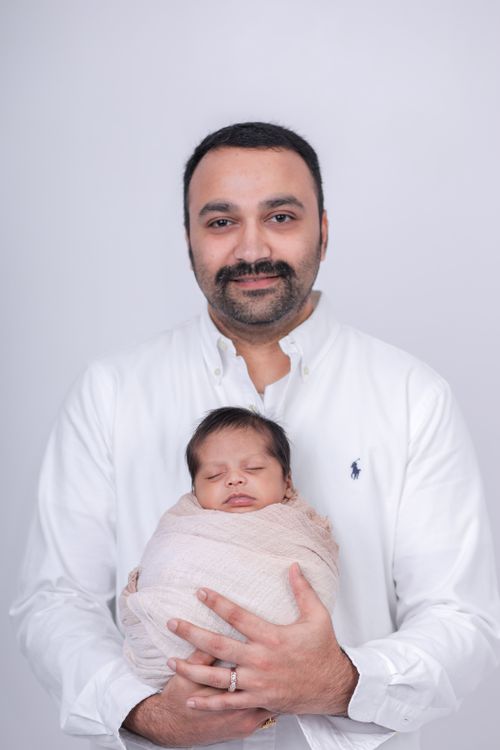 Free A heartwarming studio portrait of a father holding his sleeping newborn wrapped cozily. Stock Photo