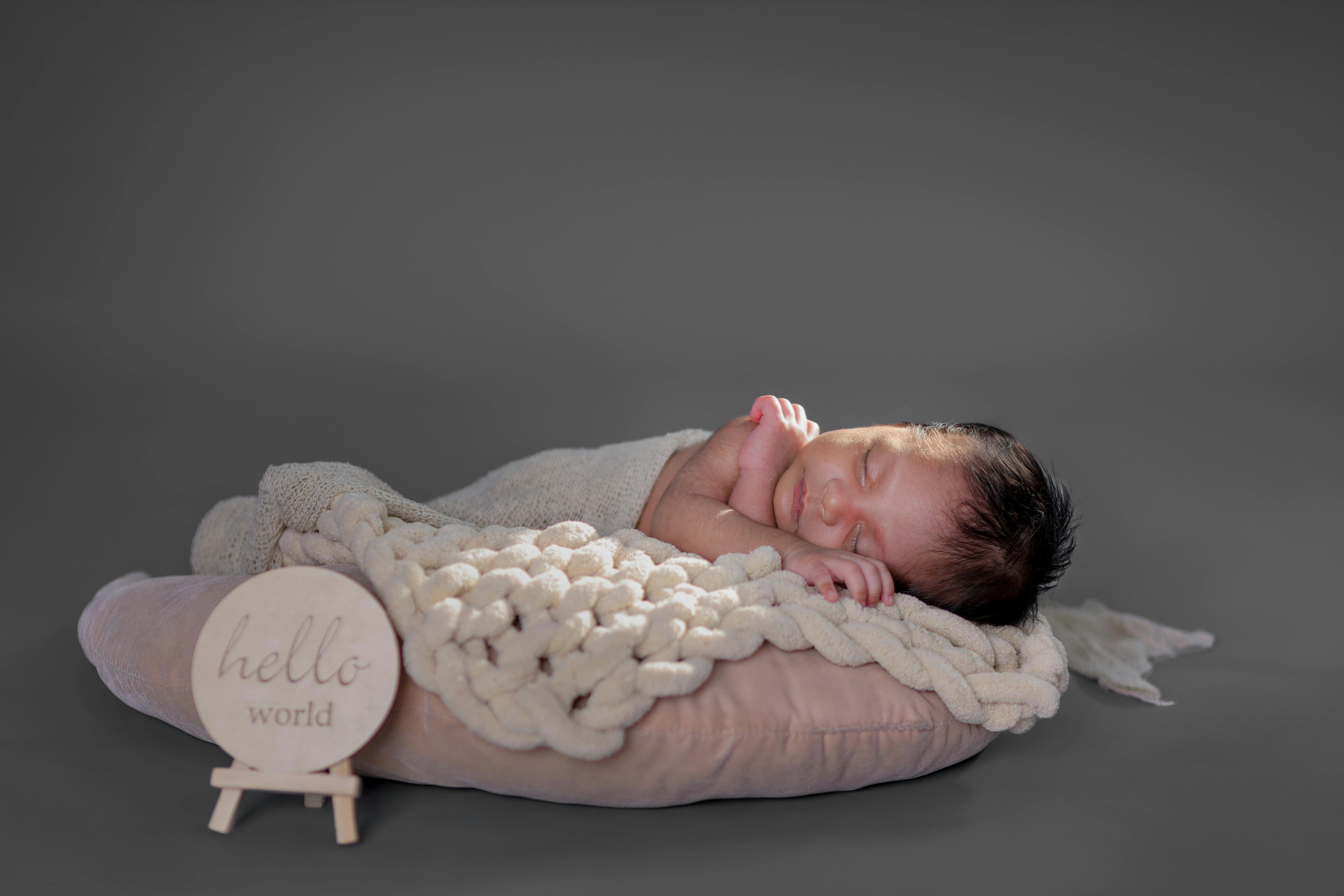 A serene image of a newborn baby sleeping wrapped in a cozy blanket with 'hello world' sign, perfect for family and baby themes.