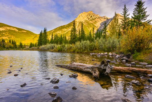 Beautiful autumn landscape of Mount Lorette Ponds in Kananaskis, Alberta, showcasing serene waters and rugged mountains.