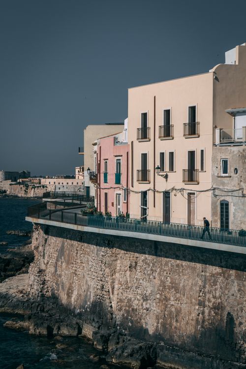 Free Scenic view of colorful seaside buildings on a rocky coastline in Italy, under a clear blue sky. Stock Photo