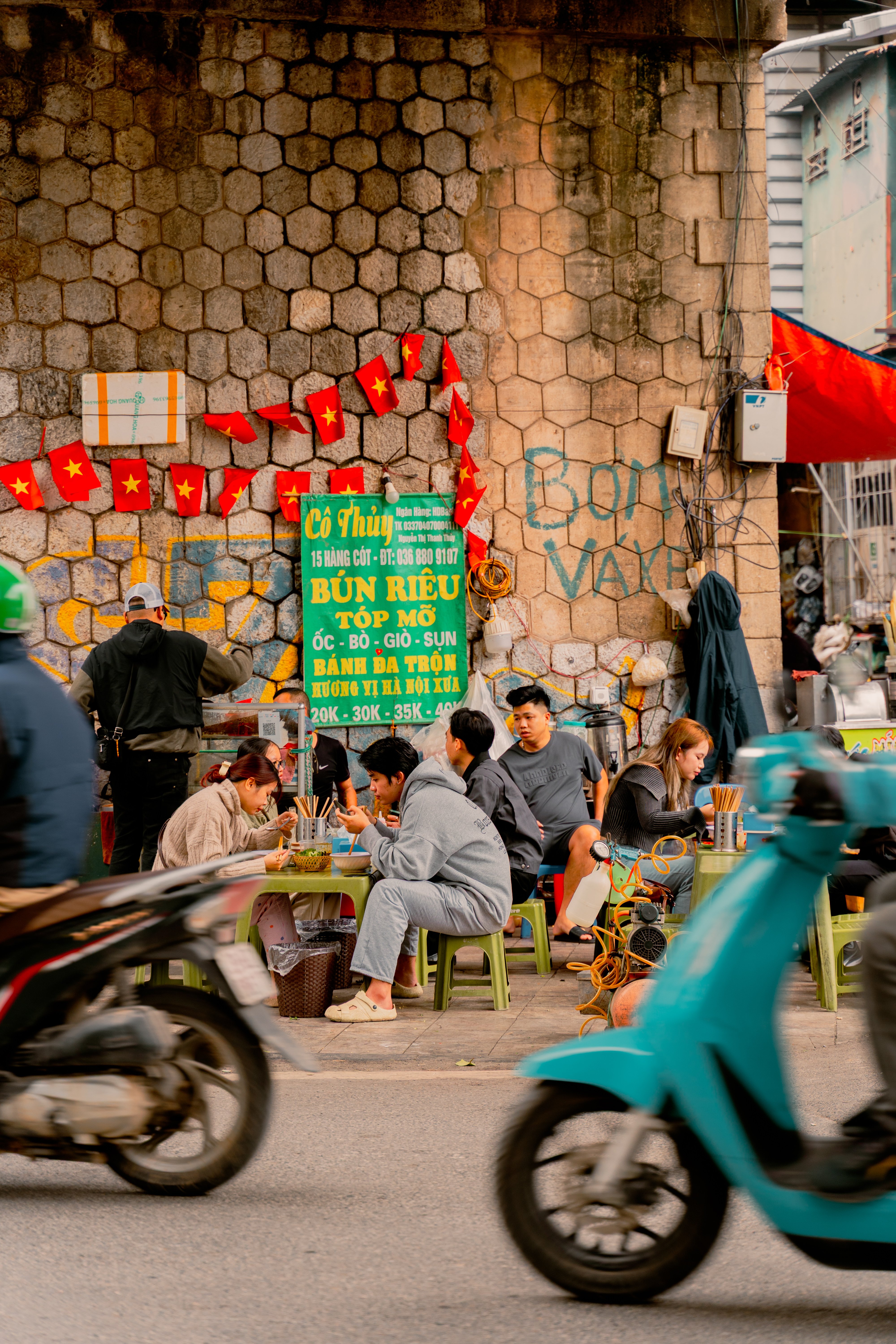Locals eating on plastic stools at a busy roadside warung in Bali under a simple tin roof