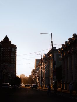 Urban street scene at sunset showcasing silhouetted buildings and city life in warm lighting.