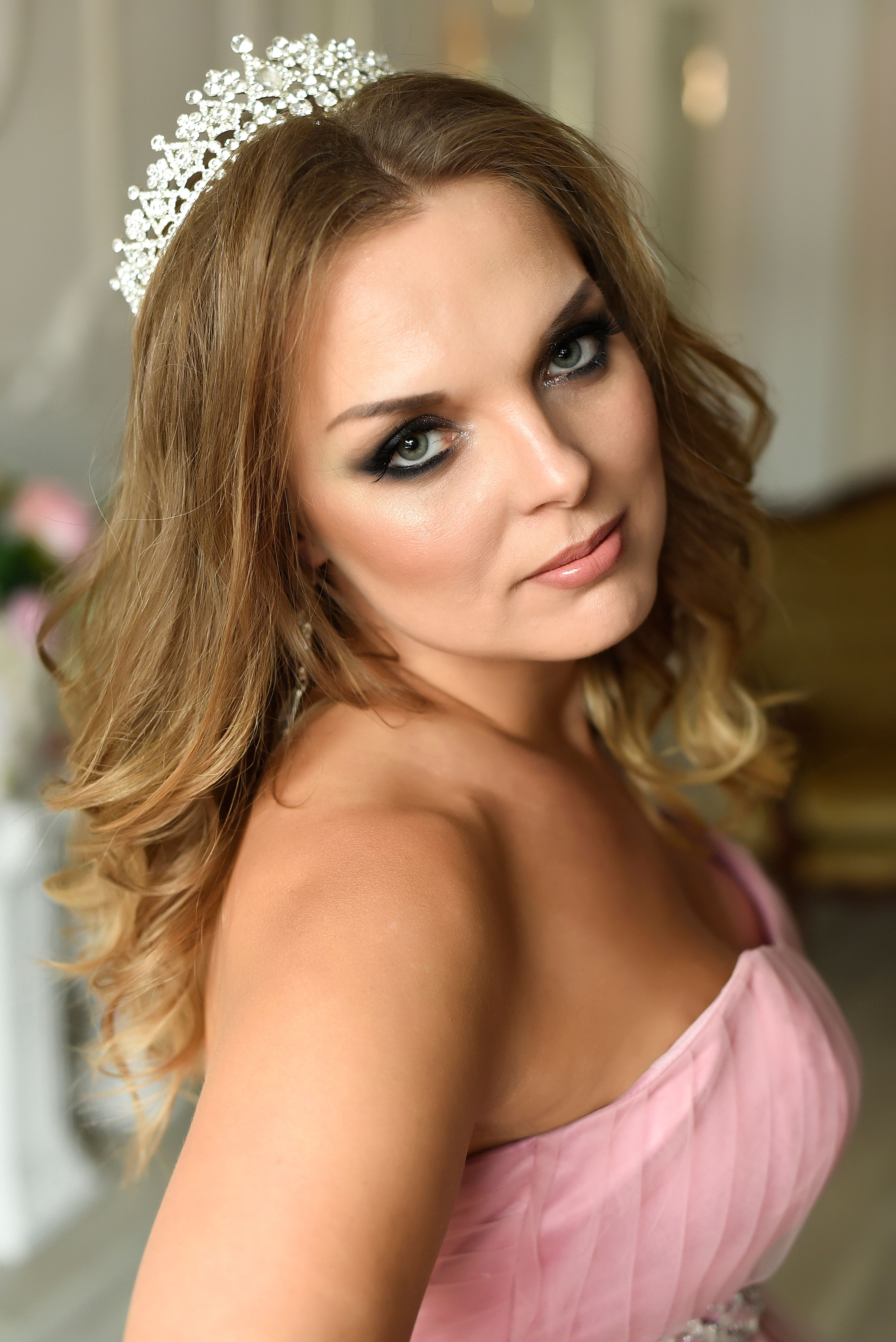 Beautiful portrait of a woman in pink gown with a tiara, highlighting elegance and glamour.