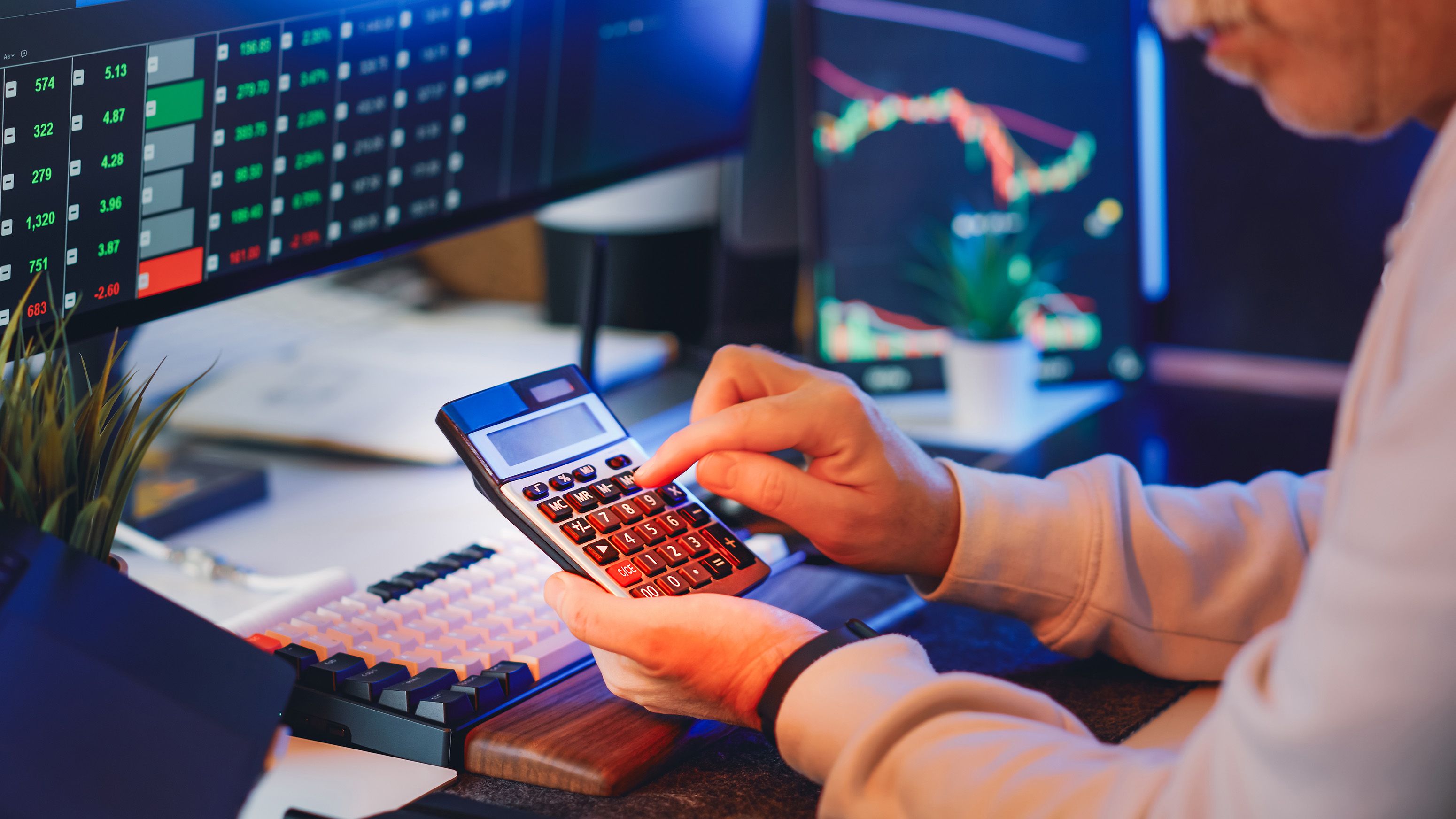 Investor desk with market charts across multiple screens