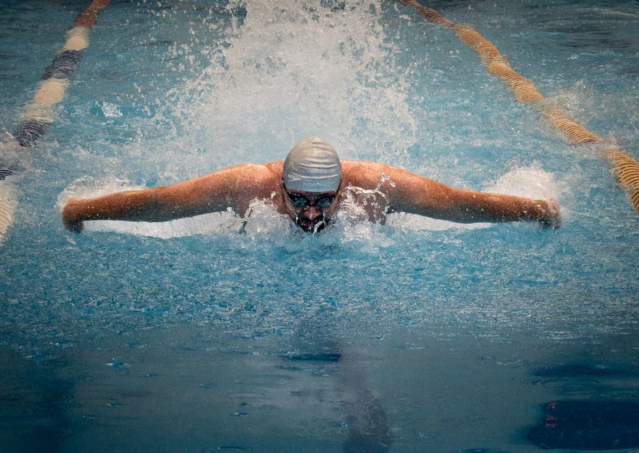 A focused swimmer competes in a pool, capturing the intensity of the butterfly stroke.
