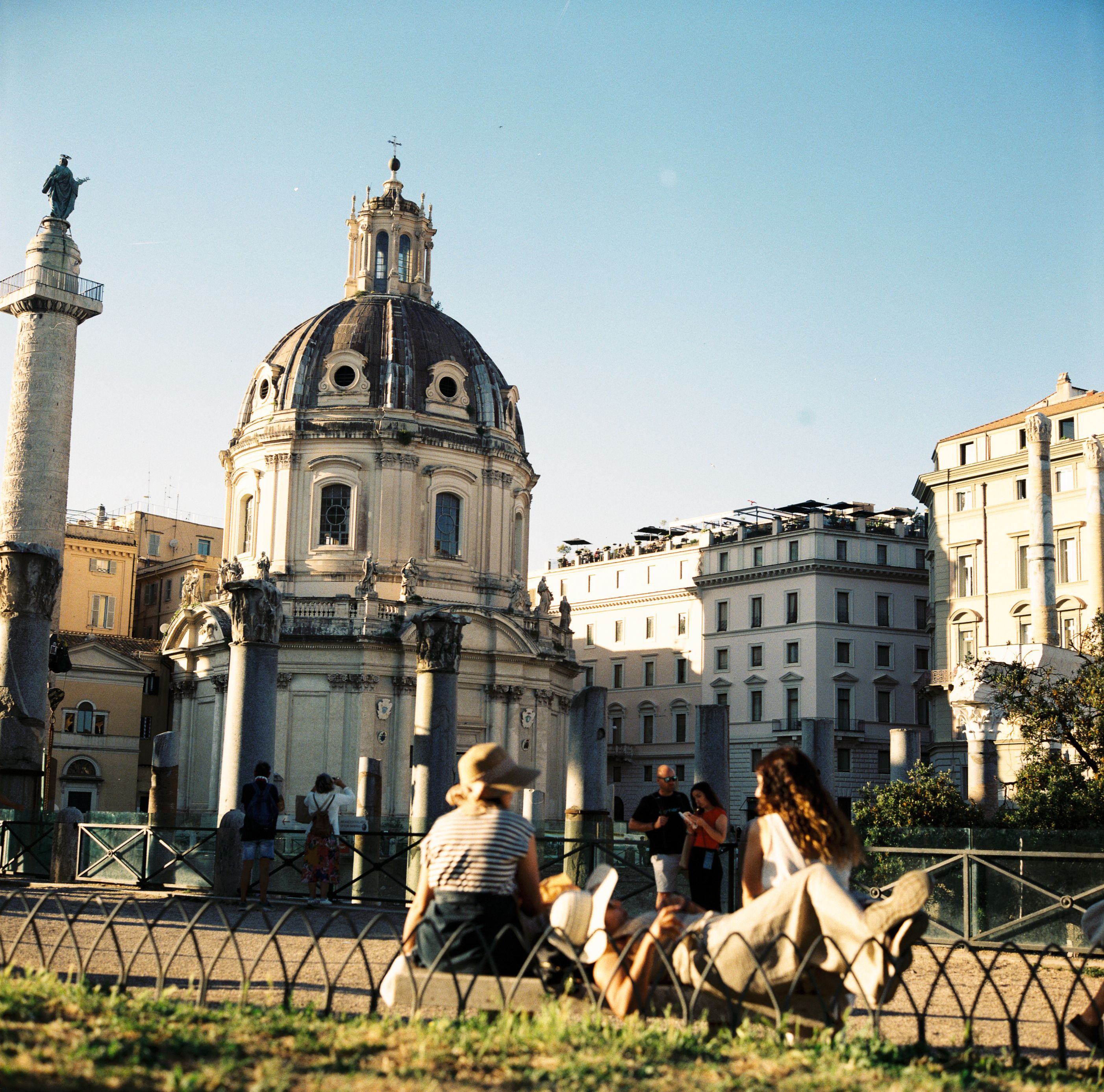 People relaxing near an iconic Roman church on a sunny day in Rome, Italy.