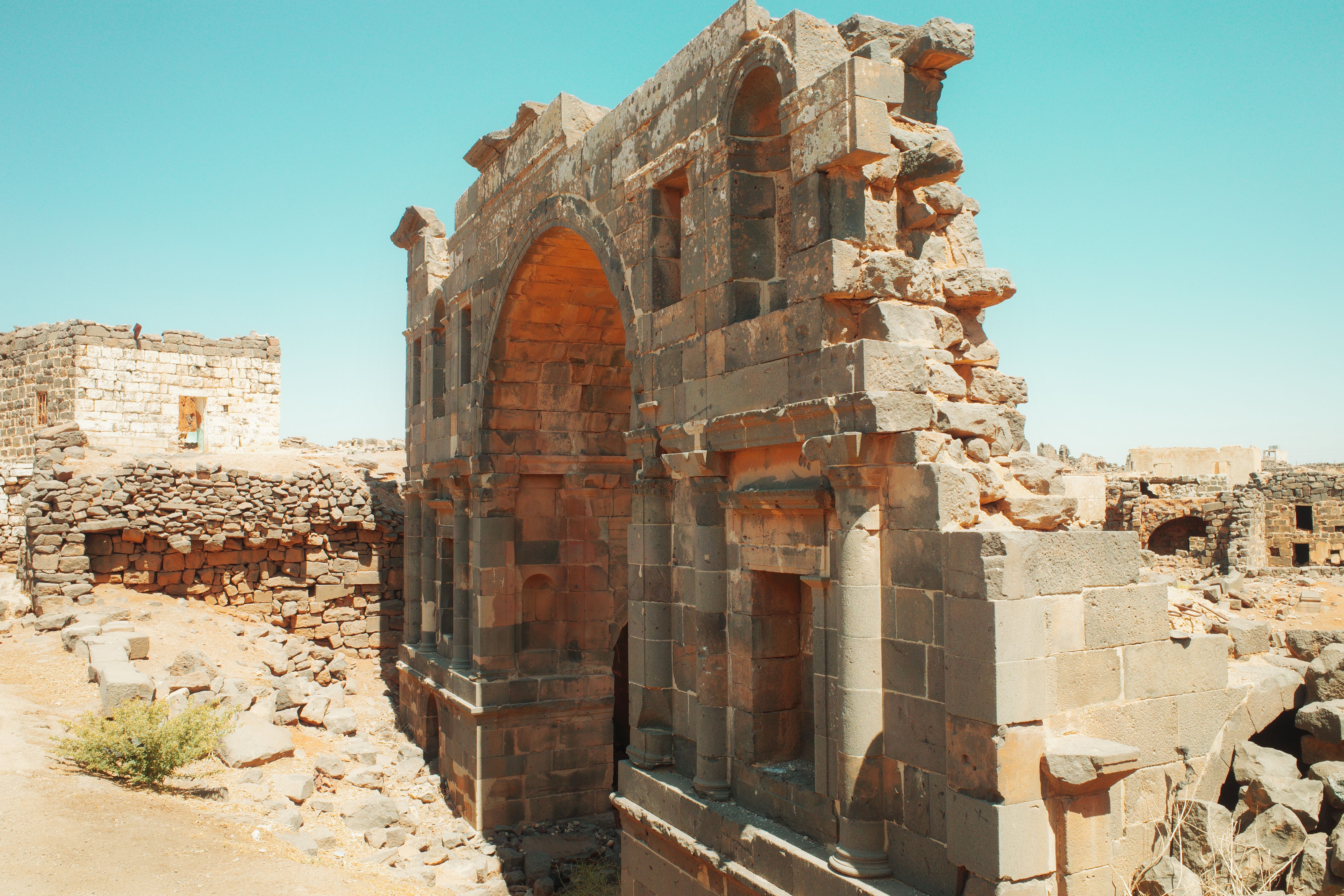 Explore the ancient stone architecture of Busra, Syria, showcasing historic ruins under a bright blue sky.