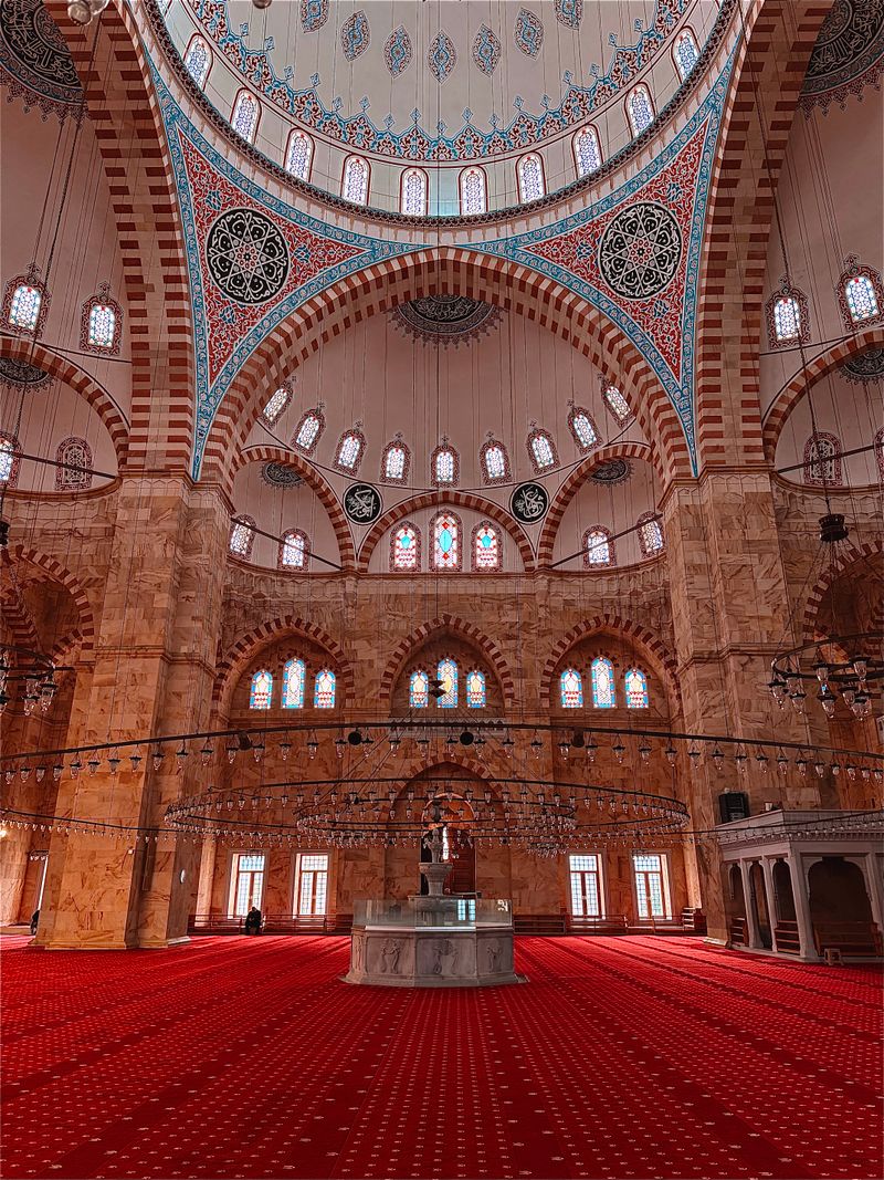 Mosque interior with intricate arches and vibrant red carpet