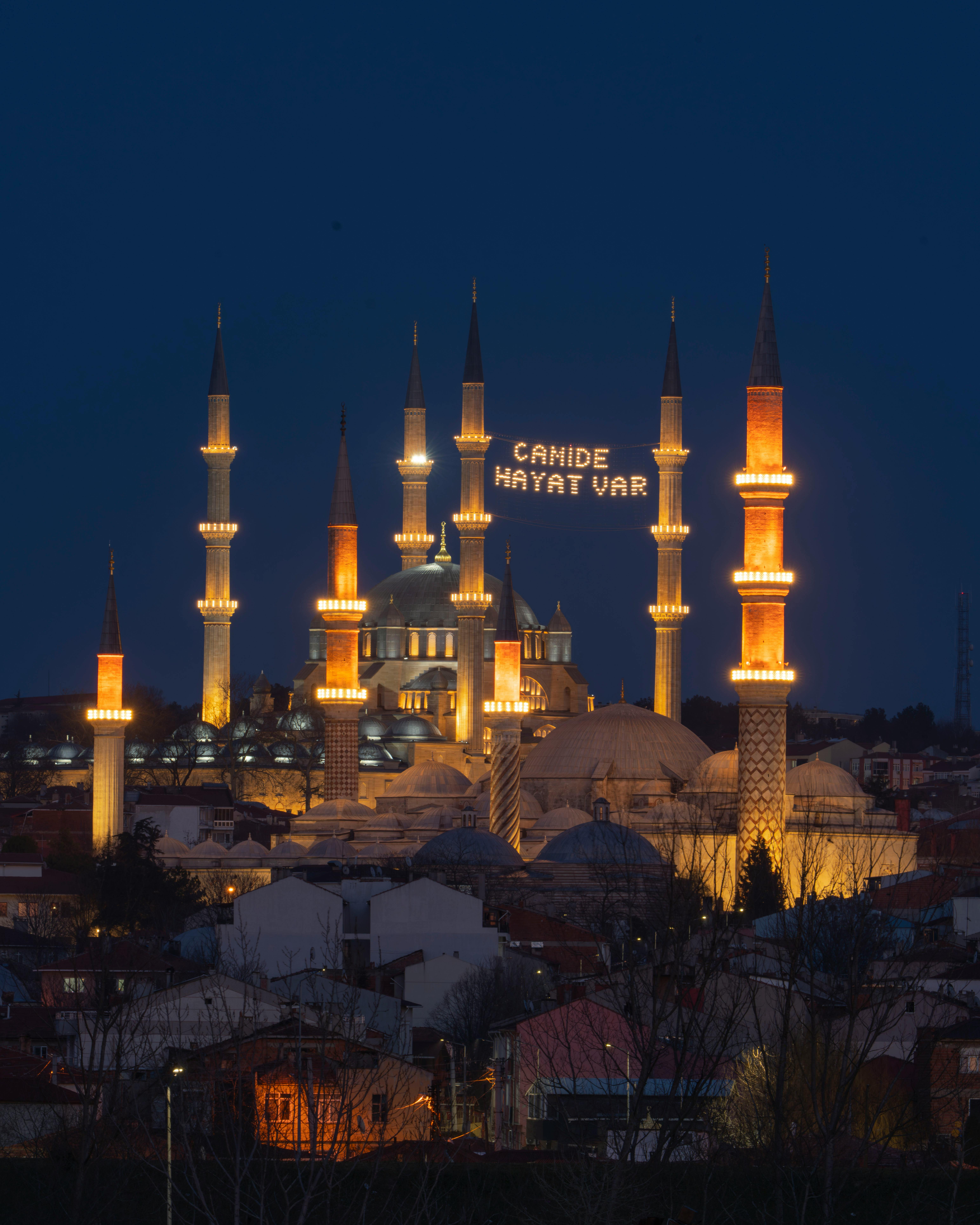 Illuminated grand mosque with minarets against the night sky, showcasing architectural beauty.