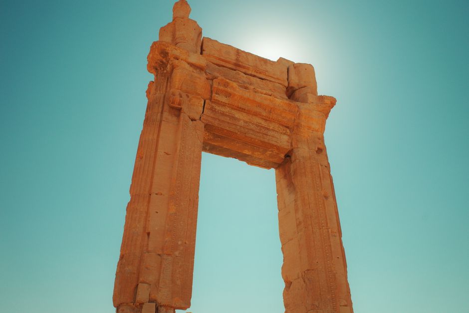 Majestic ancient stone archway under clear blue skies in Palmyra, Syria highlighting historical heritage.