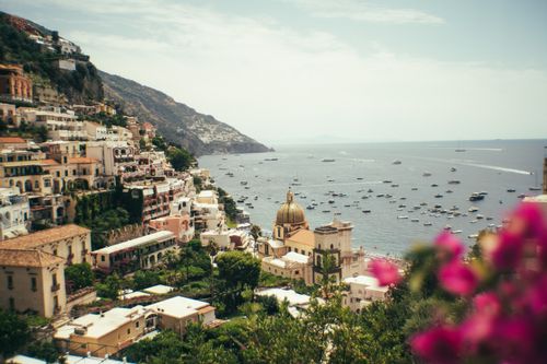 Free Scenic view of Positano's iconic cliffside and azure Mediterranean Sea with vibrant flowers. Stock Photo
