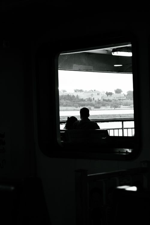 Free Silhouette of a couple seated on a ferry, framed by a window, capturing a serene and romantic moment. Stock Photo