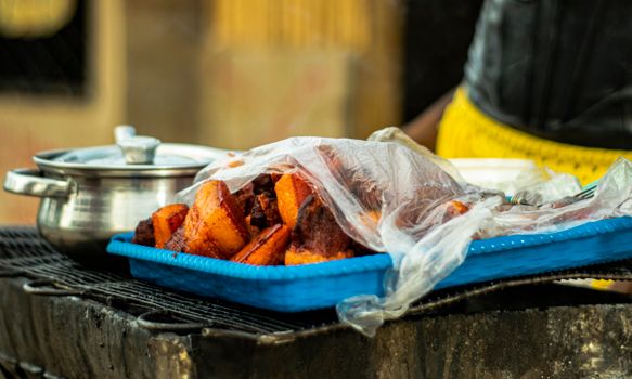 Close-up of grilled yams in a street food setting, showcasing vibrant colors and traditional methods.