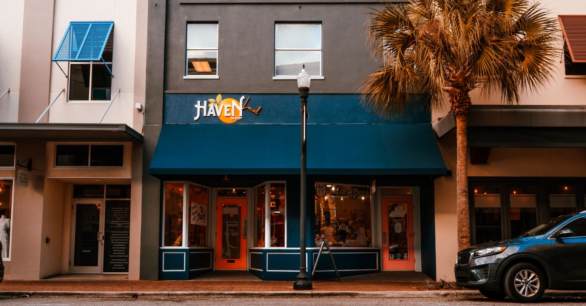 Street view featuring a boutique storefront with palm tree and vibrant colors.