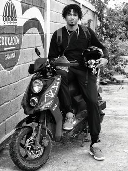 Black and white portrait of a man posing with a motorcycle outdoors in Samana.