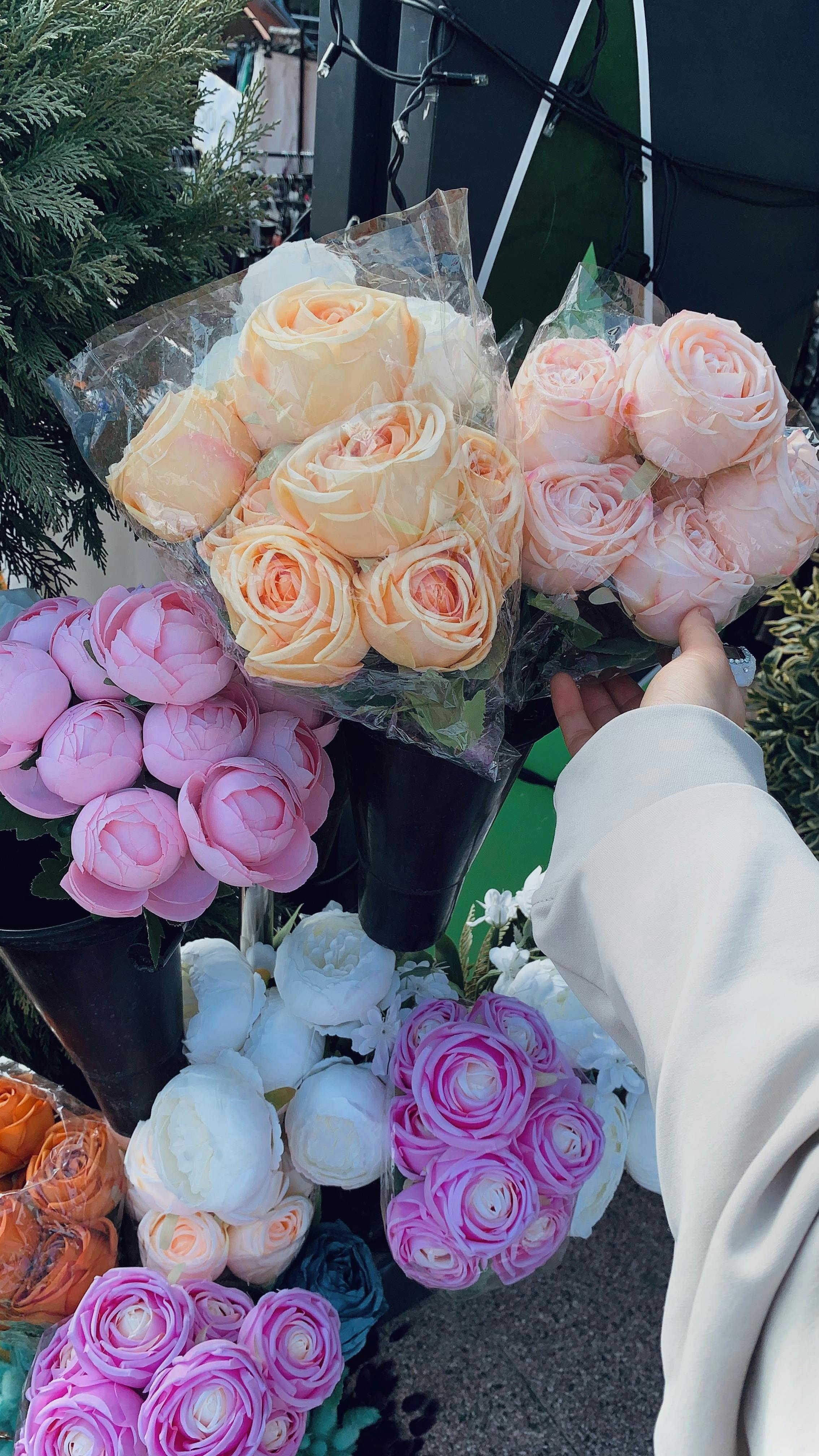 A diverse selection of colorful roses displayed at an outdoor flower market.