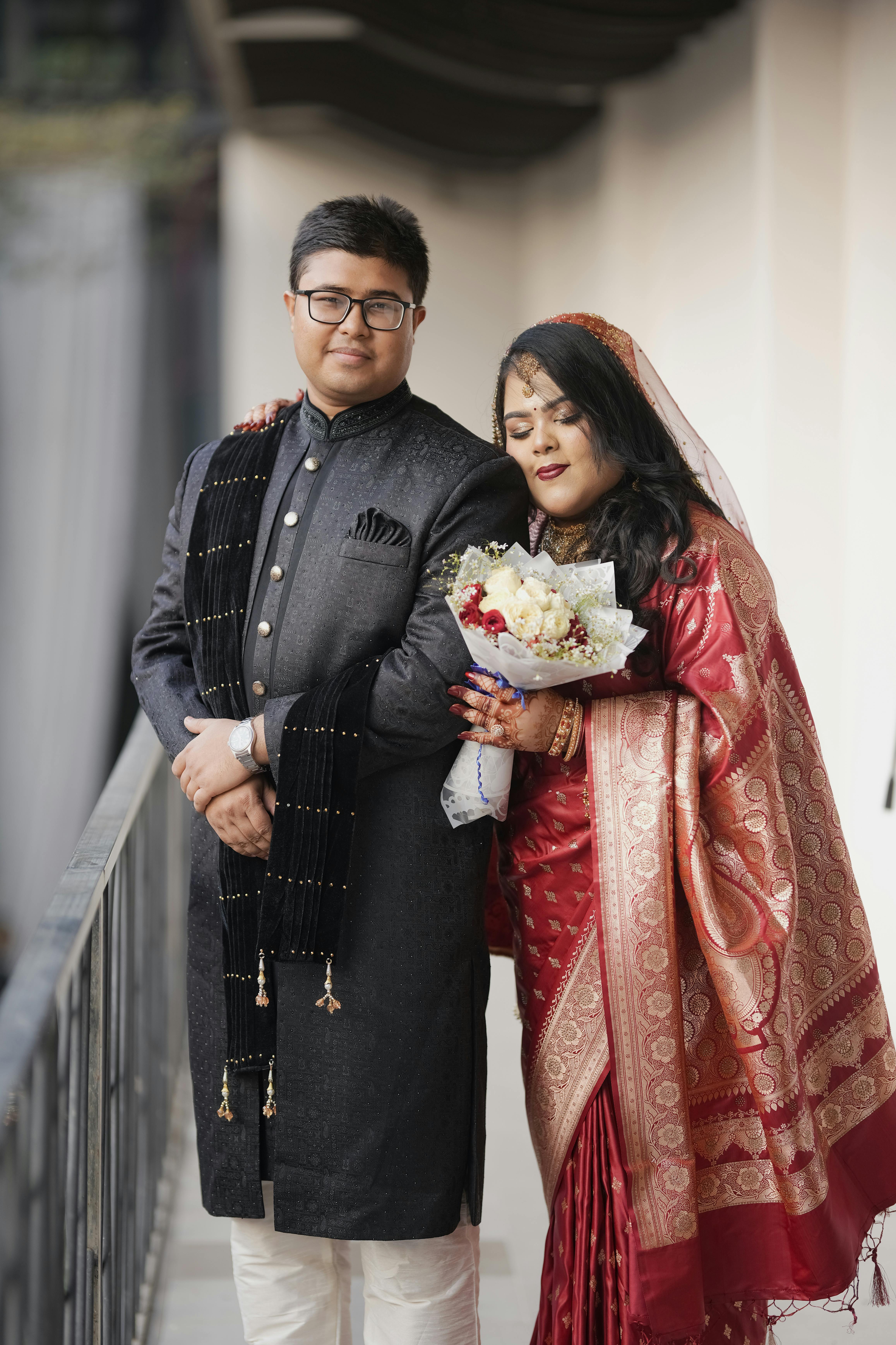 無料 伝統的な衣装を身にまとったカップルがバルコニーで抱き合い、結婚式当日のひとときを写真に収めている。 写真素材