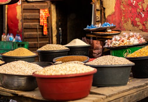 Vibrant outdoor market with various grains and spices in large bowls, creating a colorful scene.