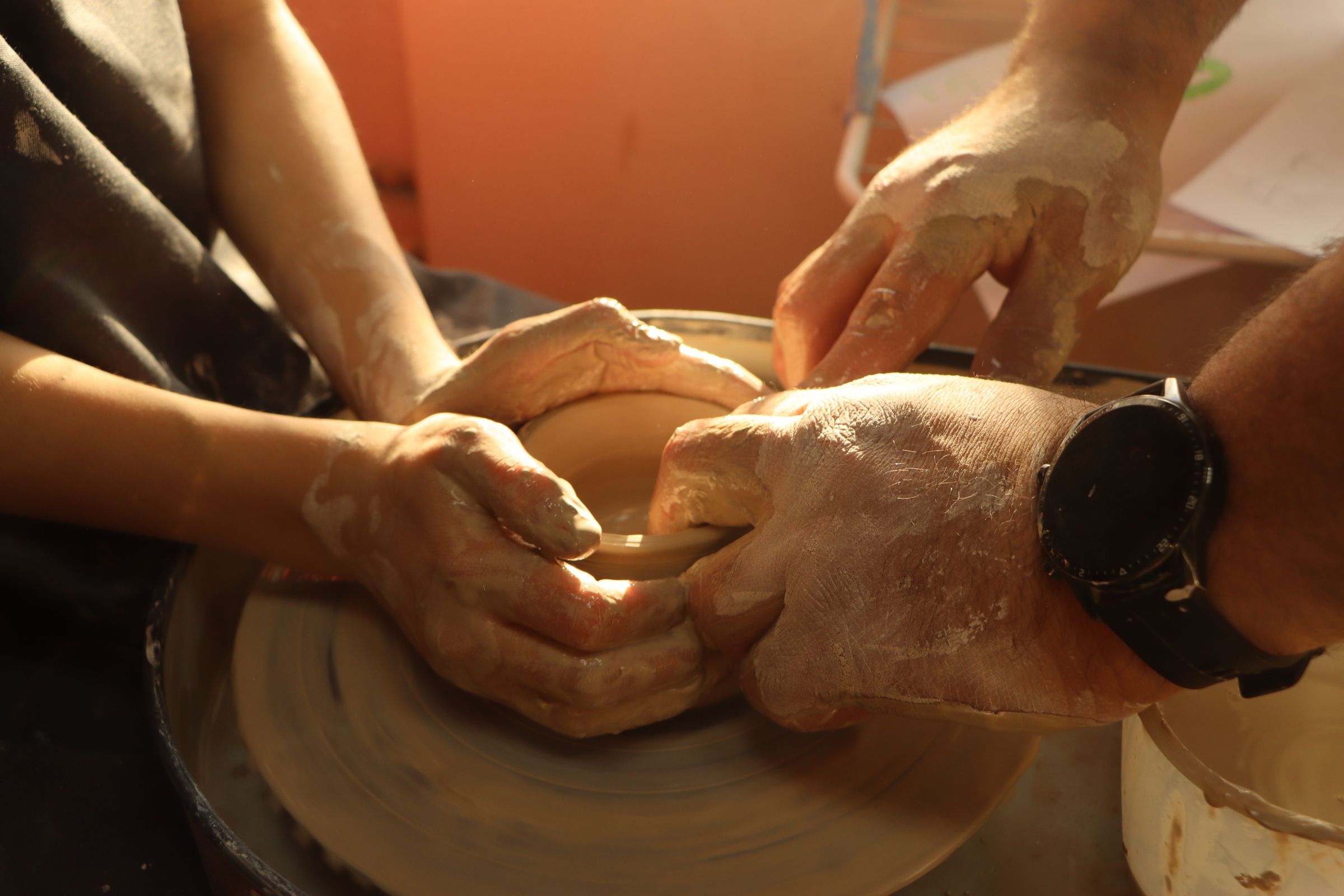 Hands shaping clay on a spinning pottery wheel