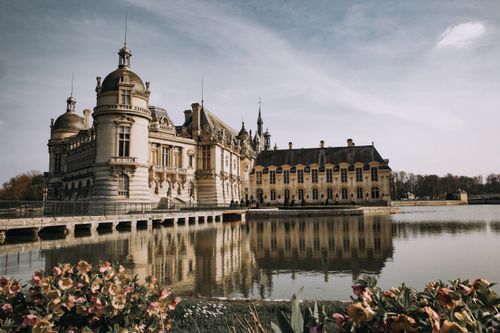 Free Elegant Château de Chantilly with its reflection on the serene lake in Hauts-de-France, France. Stock Photo