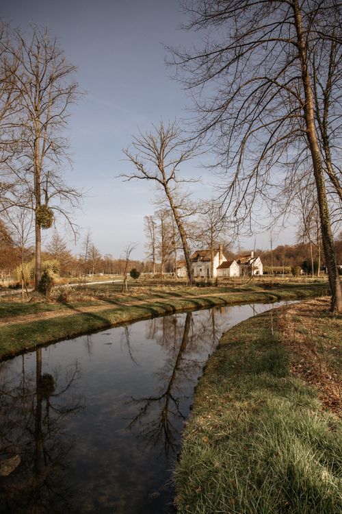 Free Picturesque view of a French chateau reflected in a tranquil pond, surrounded by winter landscape. Stock Photo