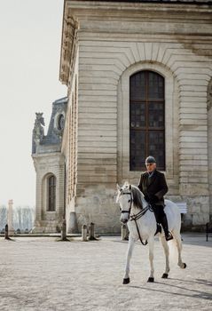 A rider on a white horse near the Chateau de Chantilly in France.