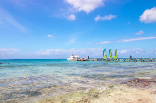 Free Scenic view of a vibrant seaside in Curaçao with clear waters, a boat, and a pier. Stock Photo