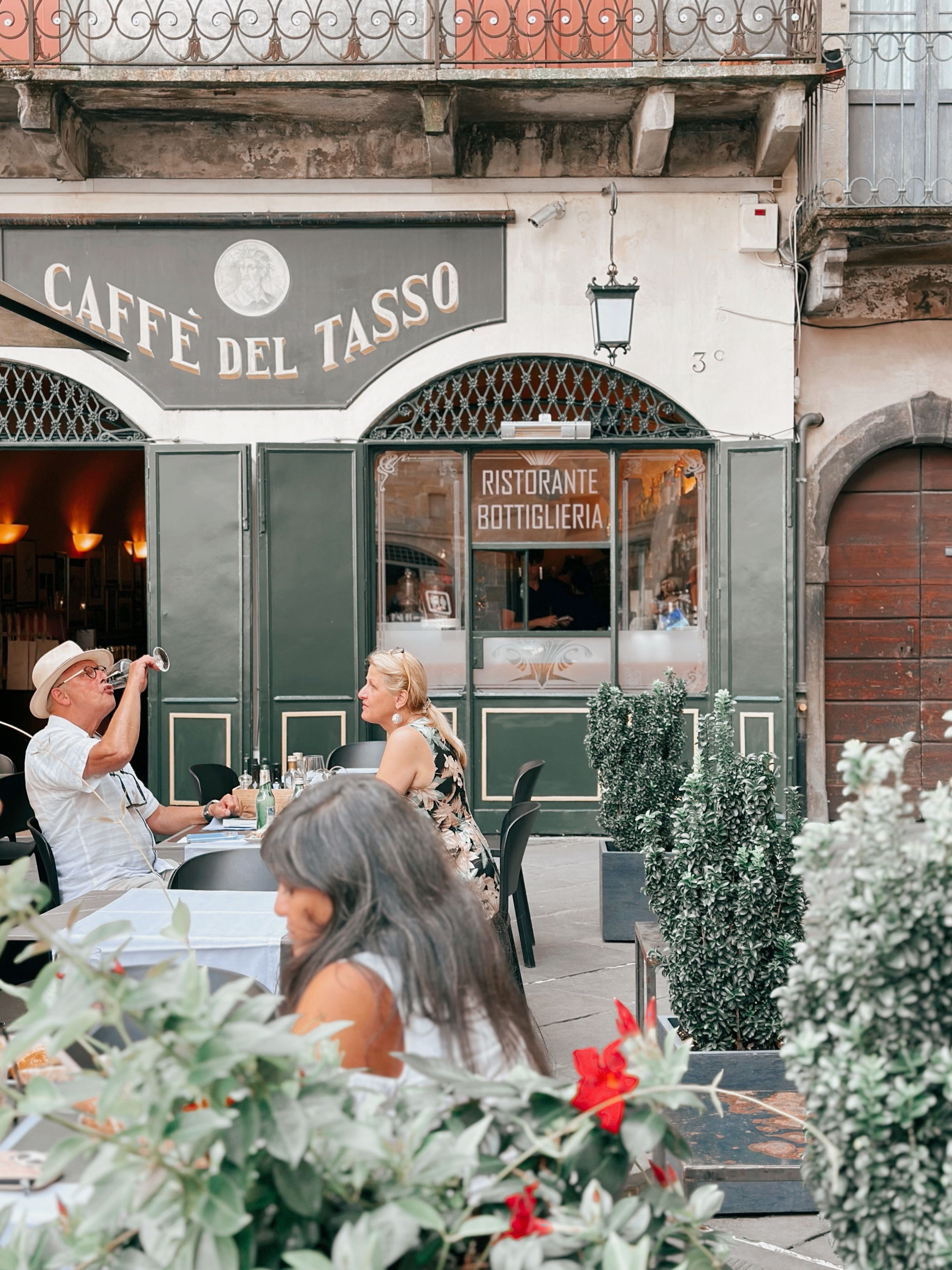 Candid scene at Caffè del Tasso in Bolzano, Italy, capturing outdoor dining ambiance with relaxed guests.