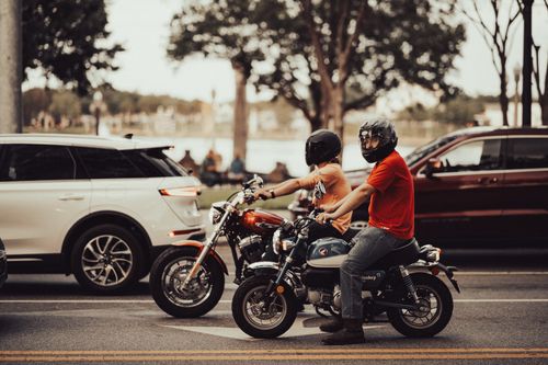 Free Motorcyclists waiting at a crosswalk in the city, wearing helmets for safety. Stock Photo