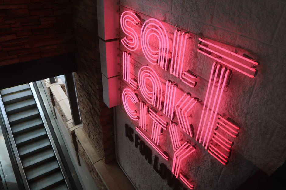 Vibrant pink neon sign displaying 'Salt Lake City' in a modern architectural setting.
