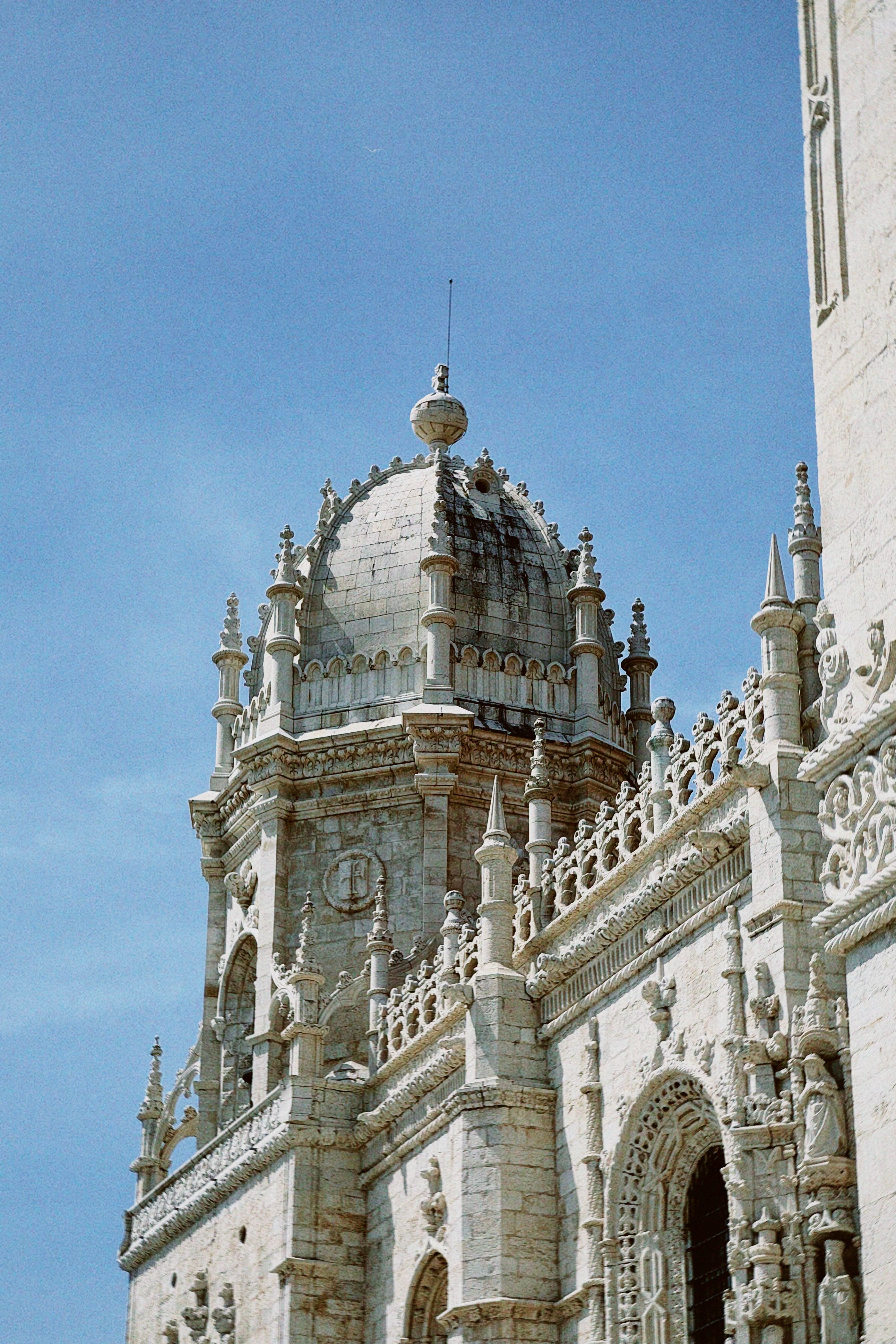 Stunning view of Jerónimos Monastery showcasing its intricate Gothic architectural details against a clear blue sky.