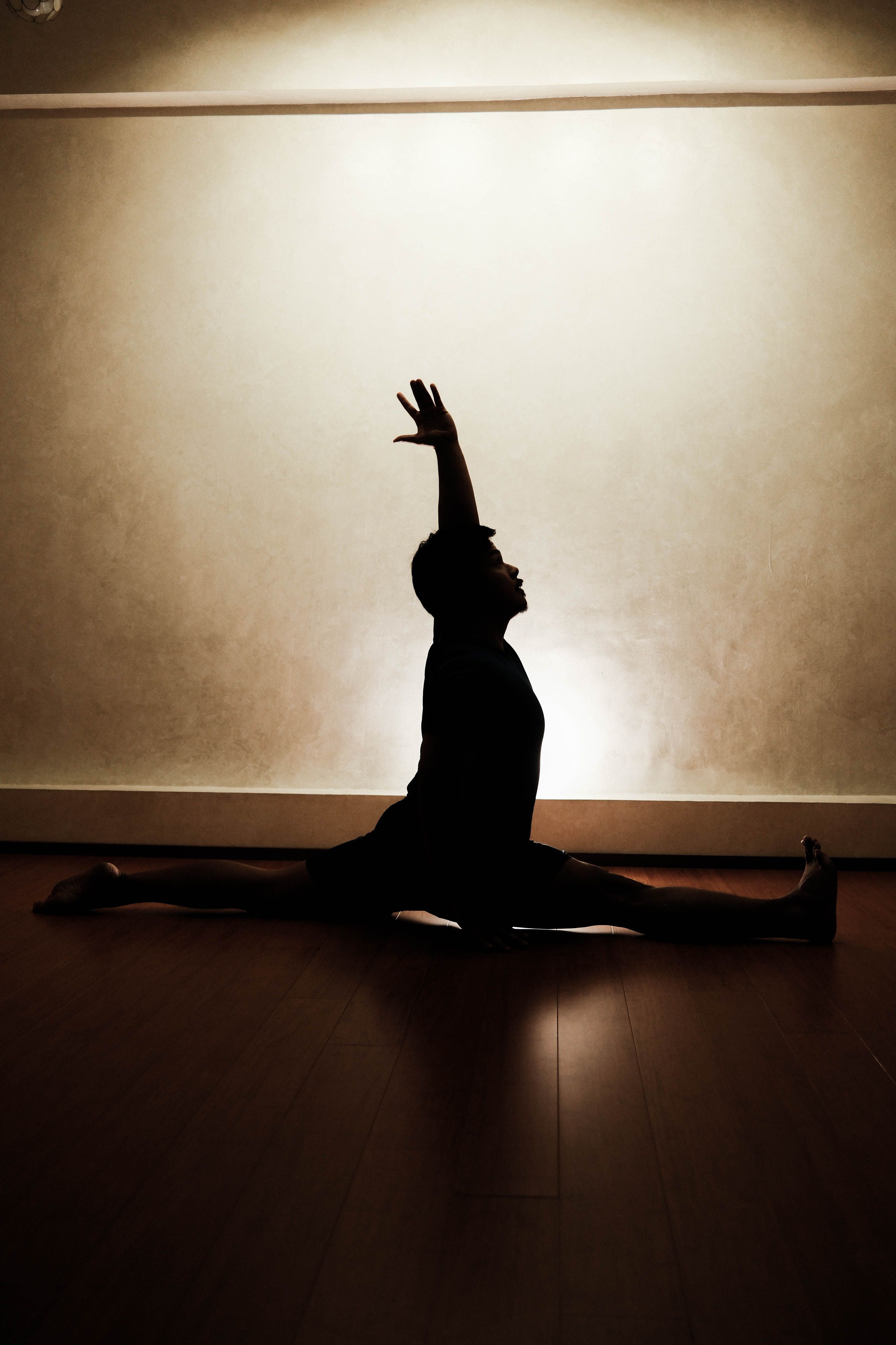 Silhouette of man performing yoga split in serene setting
