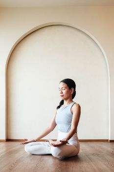 A woman practicing yoga meditation indoors in a peaceful modern setting.