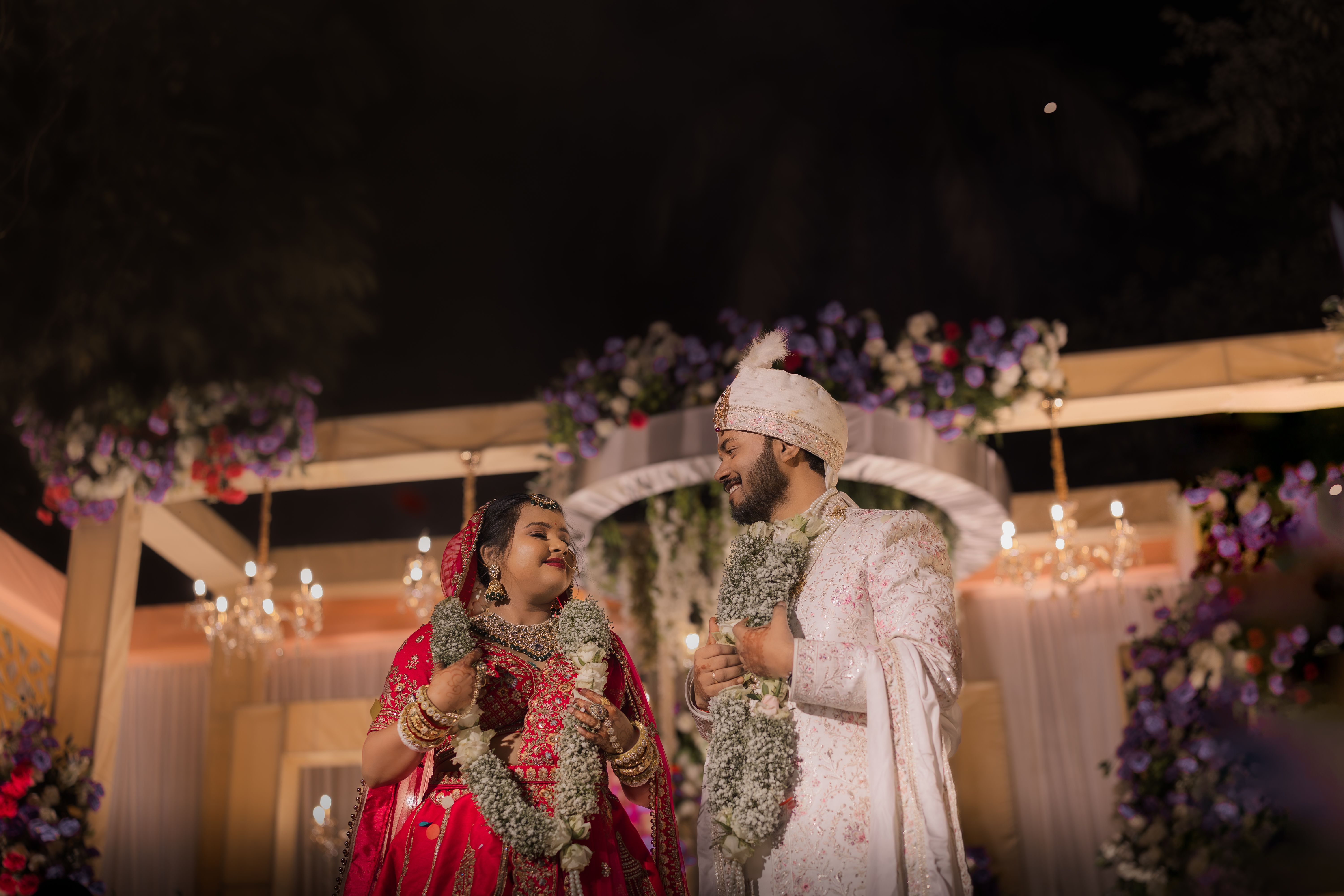 Traditional Bengali wedding featuring a bride and groom in vibrant attire with floral garlands.
