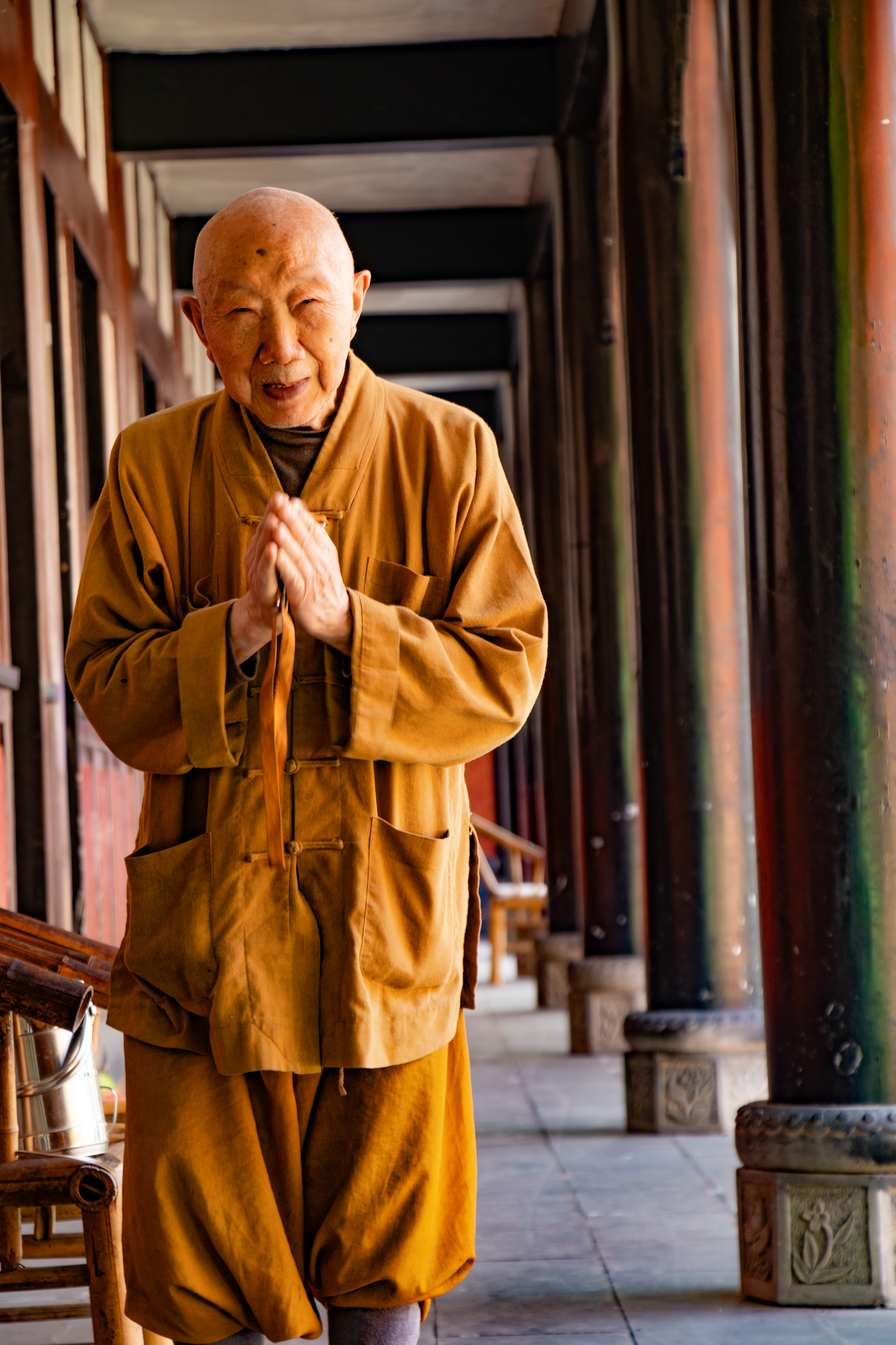 Elderly Monk Praying in Traditional Temple Corridor · Free Stock Photo