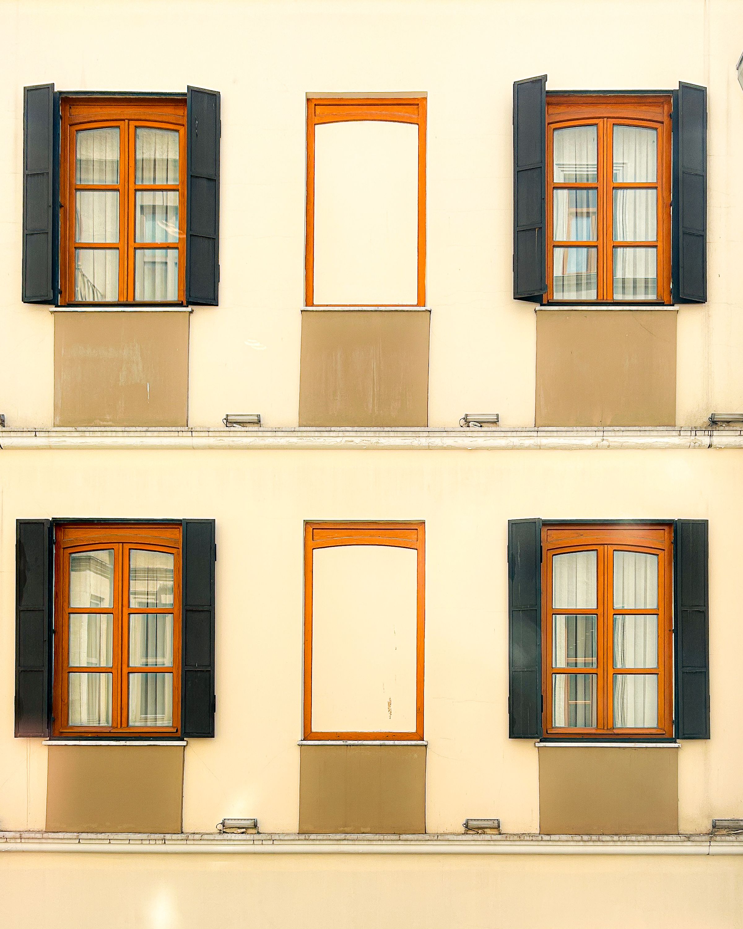 Close-up of a building facade with symmetrical wooden windows and black shutters.