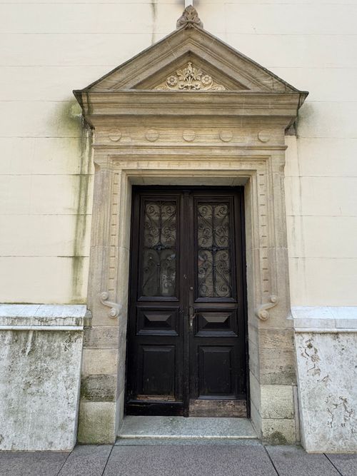 Free A detailed view of a historic wooden door with intricate carvings on a European building facade. Stock Photo