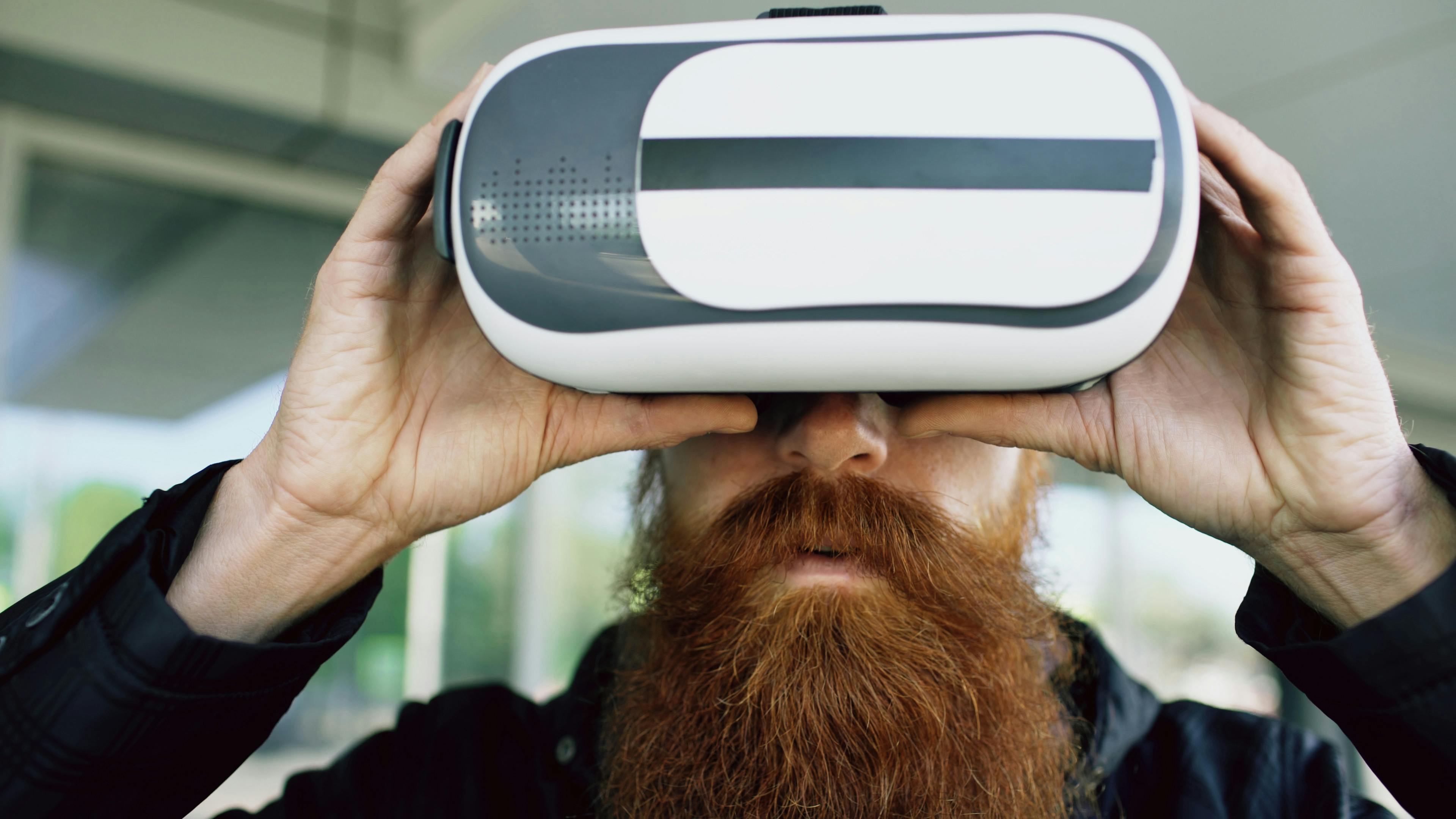 A bearded man using VR headset outdoors, immersing in a virtual experience.