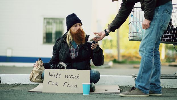 A bearded homeless man receives food from a passerby outdoors. — photo by Vitaly Gariev