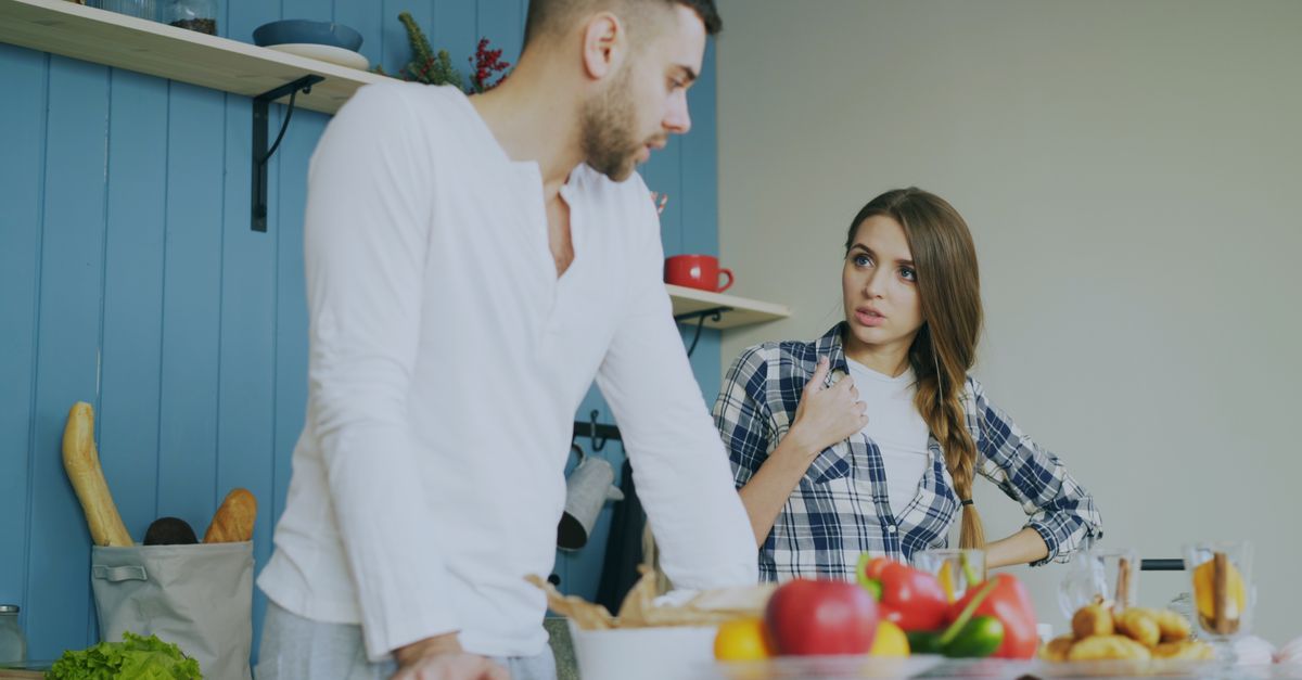 Young couple engaged in a conversation in a stylish kitchen with fresh fruits.